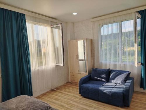 a living room with a blue couch and windows at gulelebi in Tʼianetʼi