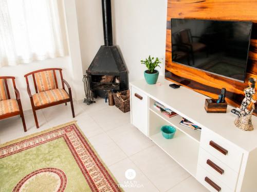 a living room with a tv and a fireplace at Pousada Casa do Reiki - Rancho Queimado/SC in Rancho Queimado