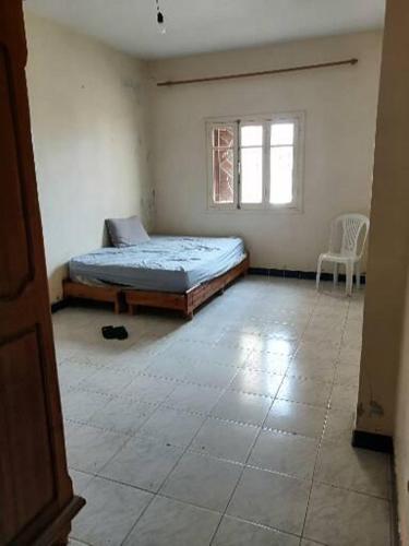 a bedroom with a bed and a window and a chair at Akr appartement in Al Hoceïma