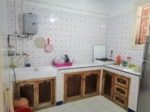 a kitchen with wooden cabinets and white walls at Akr appartement in Al Hoceïma