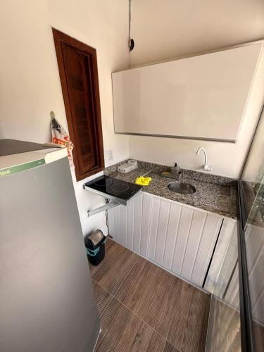 a kitchen with a sink and a refrigerator at Agradável Kitnet próximo à Praia do Forte in Mata de Sao Joao