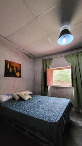 a bedroom with a bed with a blue comforter and a window at Kallpa Warmi in San Antonio