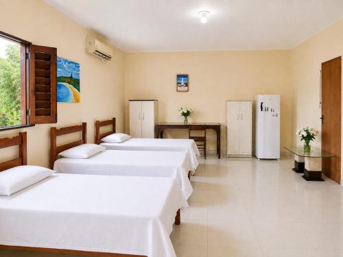 a room with four beds and a table and a refrigerator at Rooftop na lagoa in Jijoca de Jericoacoara