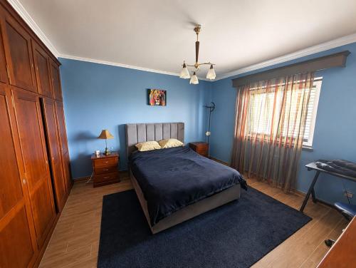 a bedroom with a bed with blue walls and a window at Moradia da Graça Guesthouse in Praia da Vitória