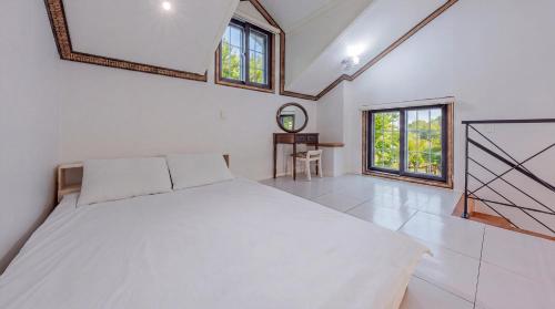 a bedroom with a large white bed and windows at Gapyeong Hue 910 Pension in Gapyeong