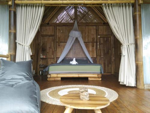 a bedroom with a bed and a table and a couch at Aska Bamboo House in Tampaksiring