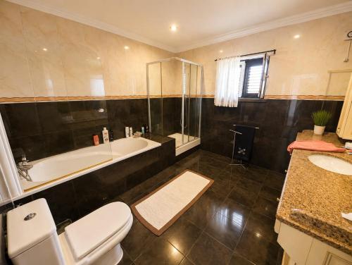 a bathroom with a tub and a toilet and a sink at Moradia da Graça Guesthouse in Praia da Vitória