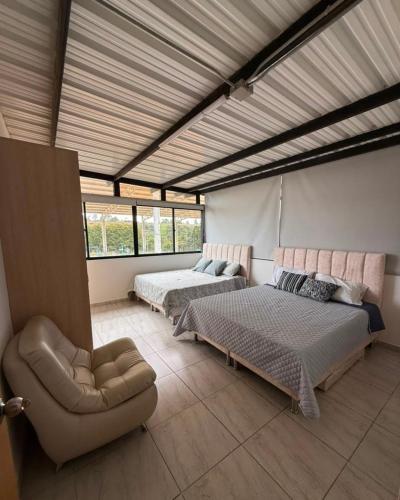 a bedroom with two beds and a chair in it at Refugio raices in Guarne
