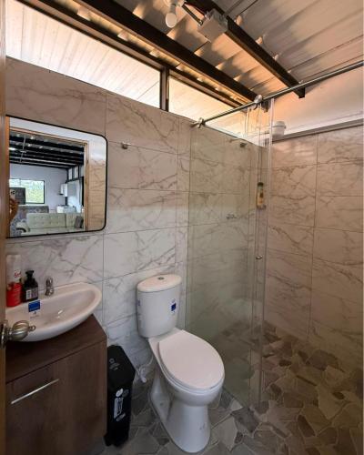 a bathroom with a toilet and a sink and a shower at Refugio raices in Guarne