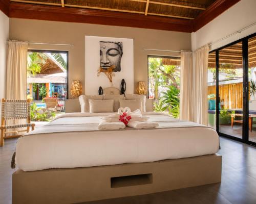 a bedroom with a large white bed with a flower on it at Villa Kasadya in Panglao Island