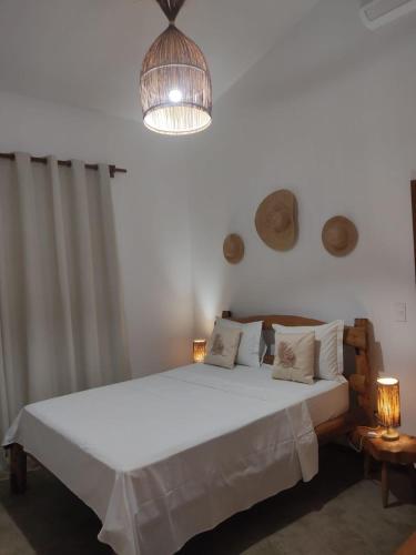 a bedroom with a large white bed with two lamps at Prédio em praça pontal de Maceió in Fortim