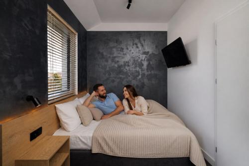 a man and a woman sitting on a bed at Apartamenty Racławicka Mszczonów in Mszczonów
