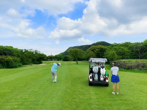a man and woman playing golf with a golf cart at Ecoland Hotel in Jeju