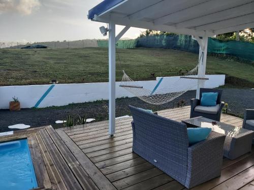 a porch with a hammock and a swimming pool at Bungalow chic à Sainte-Rose + piscine. in Sainte-Rose