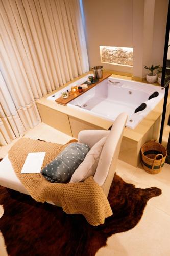 a bath tub in a room with a chair and a rug at Moldavite Bungalow in Treze Tílias