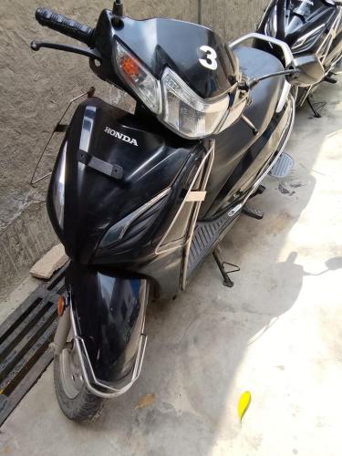 a black motor scooter parked on a street at RadhaRaman StayInn in Mathura