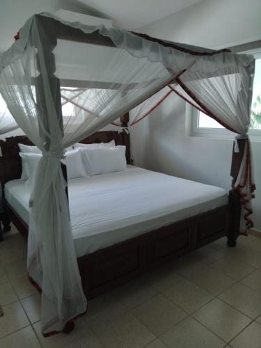 a bed with a canopy in a room at Maasai Resort in Mombasa