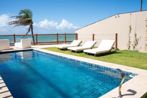 a swimming pool with lounge chairs and the ocean at Fran de Fransquinha in Taíba