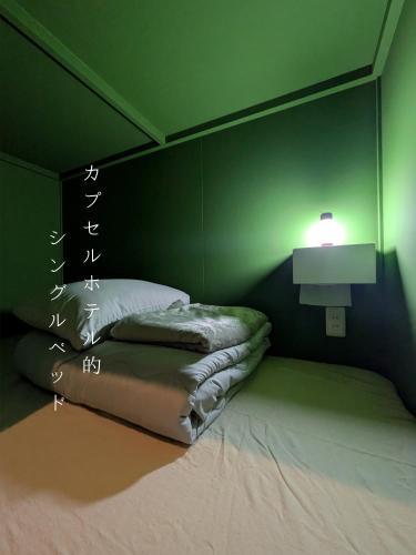a green bedroom with a bed and a lamp at Hostel x Hair ie in Hadano