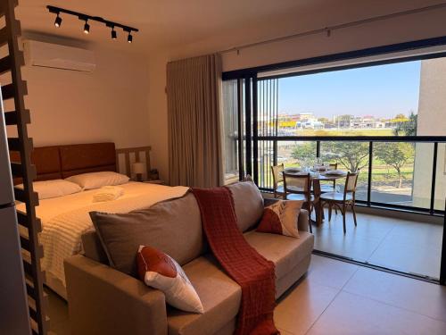 a bedroom with a bed and a couch and a table at Loft Elegante proximo do Shopping Esmeralda in Marília