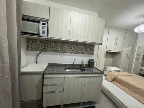 a small kitchen with a sink and a microwave at Studio Brooklyn - 3 minutos da EPCAR in Barbacena