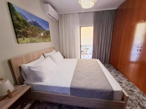 a bedroom with a large white bed with a window at Dhimarko Guest House in Përmet