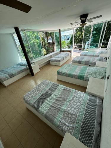 three beds sitting in a room with windows at Ven a disfrutar de Casa Alfenapa a pie del lago, somos pet friendly in Tequesquitengo