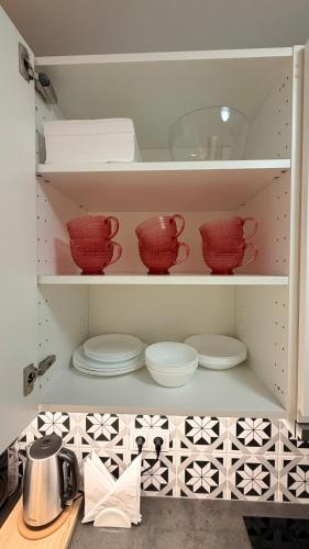 a shelf with red cups and plates in a kitchen at Studio 13 Warsaw in Warsaw