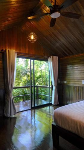 a bedroom with a bed and a large window at Lush inn Phuket in Ban Suan