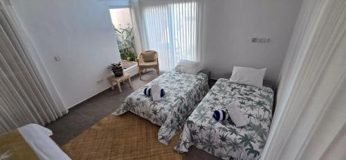 a bedroom with two beds and a chair at Villa Segara Agung Amed in Amed