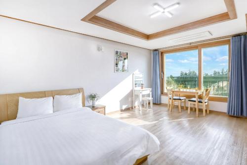 a bedroom with a bed and a table with chairs at Jeju DK House Pension in Seogwipo
