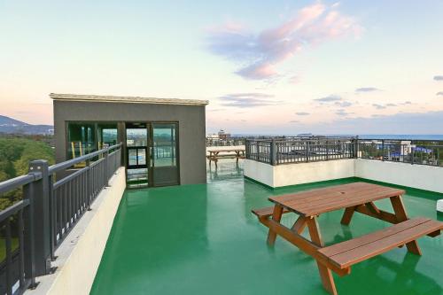a balcony with a table and benches on top at Jeju DK House Pension in Seogwipo