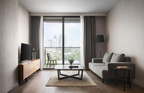 a living room with a couch and a tv at Walton Suites Sukhumvit in Bangkok