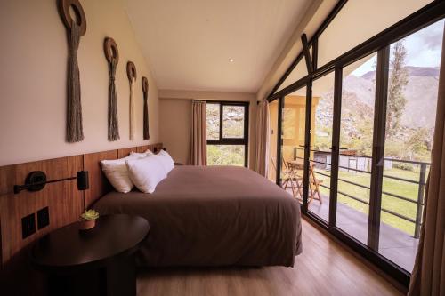 a bedroom with a bed and a large window at Earth Tones Tiny Homes & Suites in Ollantaytambo