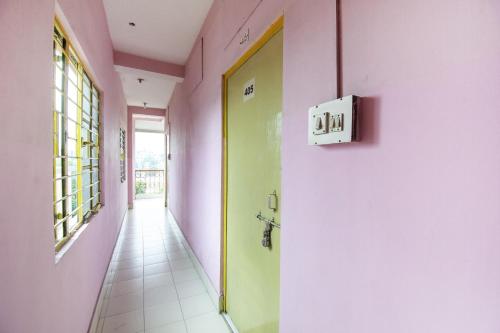 a hallway with pink and green walls and a yellow door at Hotel O Suvidha in Jamshedpur