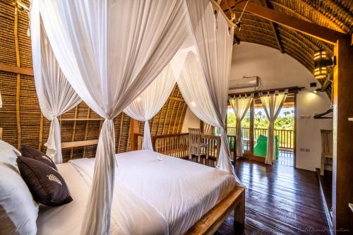 a bedroom with a canopy bed with white curtains at Bunga Laut Bungalow in Amed