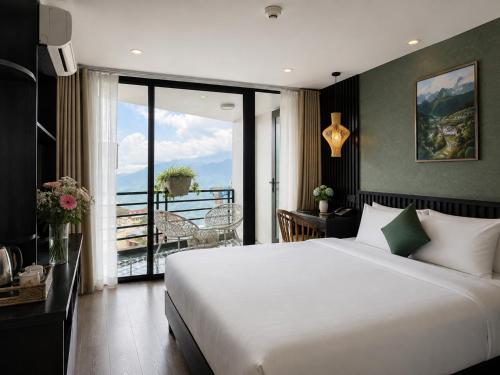 a bedroom with a large white bed and a balcony at Cloud Chaser Hotel in Sapa