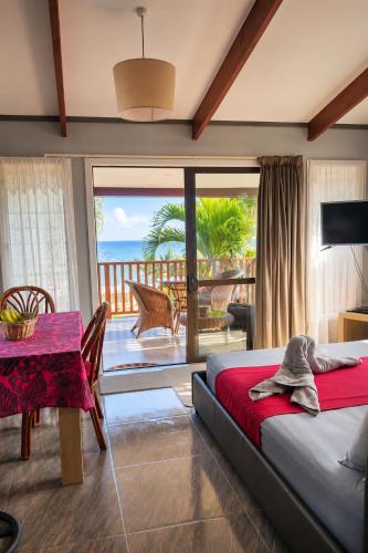 a bedroom with a bed and a table and a balcony at Sunset Palms Rarotonga in Rarotonga