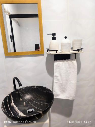 a bathroom with a sink and a mirror and towels at Tucan container in Fortuna