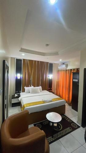 a bedroom with a bed and a table and a chair at Pretelia Hotel in Warri