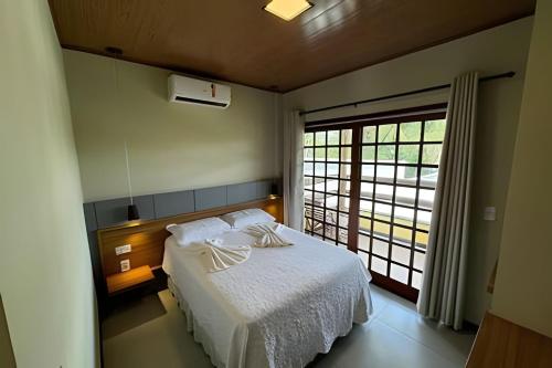 a bedroom with a white bed and a large window at Vila dos Poetas in Barreirinhas