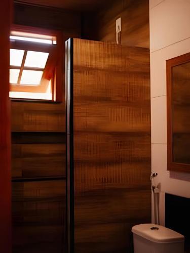 a bathroom with a toilet and a wooden wall at Vila dos Poetas in Barreirinhas