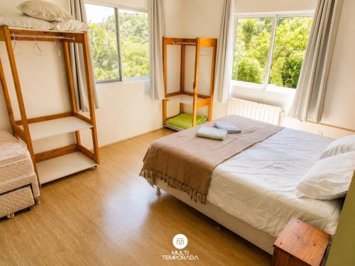 a bedroom with two bunk beds and two windows at Pousada Casa do Reiki - Rancho Queimado/SC in Rancho Queimado