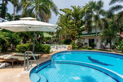 a swimming pool with an umbrella and a hotel at The Beach Wellness Residence in Ban Pru Yai