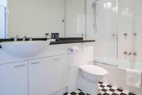 a white bathroom with a sink and a toilet at Mantra on Jolimont in Melbourne