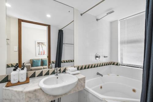 a white bathroom with a sink and a tub at Silkari The Pavilions in Port Douglas