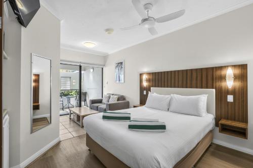 a bedroom with a large bed and a living room at Silkari The Pavilions in Port Douglas