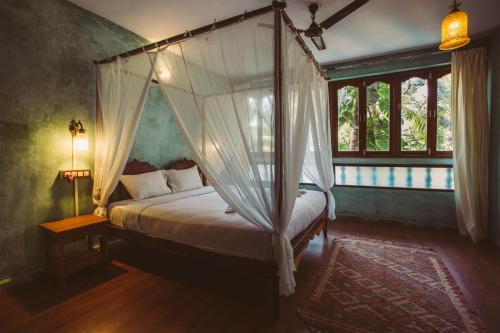 a bedroom with a canopy bed and a window at Goa Yoga Retreat in Mandrem