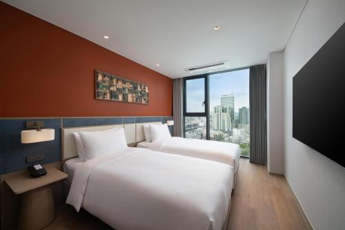 a hotel room with two beds and a flat screen tv at Mercure Ambassador Seoul Dongdaemun in Seoul