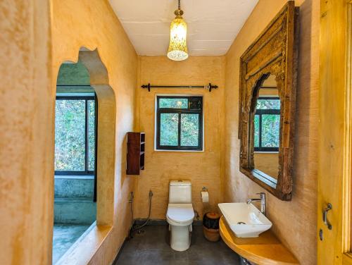 a bathroom with a toilet and a sink and a mirror at Goa Yoga Retreat in Mandrem